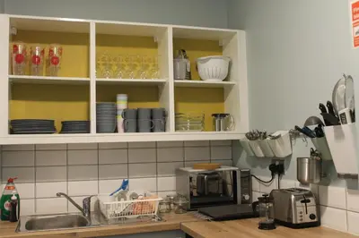 a kitchen with white cabinets with plates and glasses at Garnock House in Beith