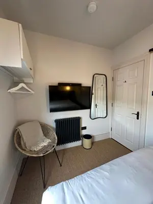 a bedroom with a bed and a mirror and a chair at Rooms Above Sugar Boat in Helensburgh