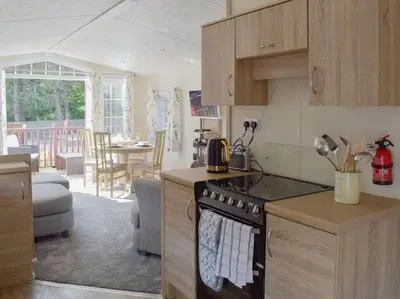 a kitchen with a stove top oven next to a living room at Poppy Lodge Glendevon Scotland in Glendevon
