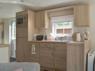 a small kitchen with wooden cabinets and a window at Poppy Lodge Glendevon Scotland in Glendevon