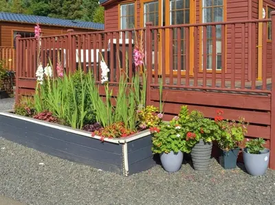 a garden with plants in pots next to a fence at Poppy Lodge Glendevon Scotland in Glendevon