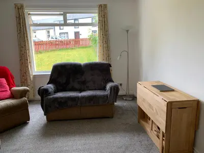a living room with a chair and a table at 10 Burns Street, Tarbolton KA5 5RA in Tarbolton
