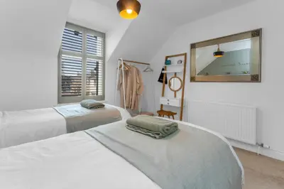 a bedroom with two beds and a mirror and a window at Beeswing, a Victorian Gem in Biggar in Biggar