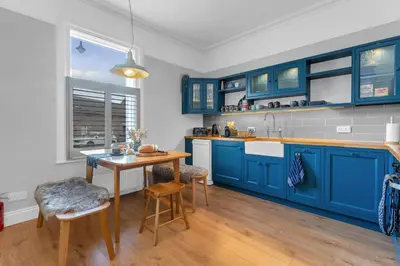 a kitchen with blue cabinets and a wooden table at Beeswing, a Victorian Gem in Biggar in Biggar