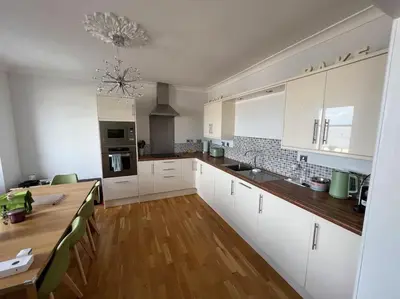 a kitchen with white cabinets and a wooden table at Fantastic 3 bedroom holiday home in Millport