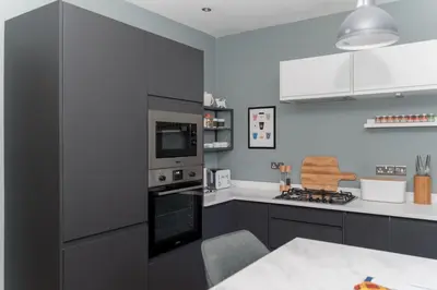 a kitchen with gray cabinets and a stove top oven at Beautiful & Bright 2BD Flat - Haymarket in Edinburgh