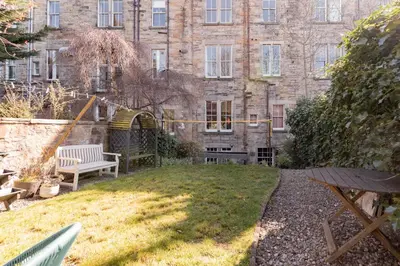 a garden with a bench in front of a building at Beautiful & Bright 2BD Flat - Haymarket in Edinburgh
