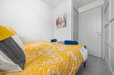 a bedroom with a bed with a yellow blanket at I'm Your Host - Bridgeton House in Glasgow