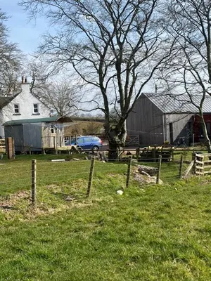 a field with a fence and a barn and a car at Granny’s Hut in Thornhill