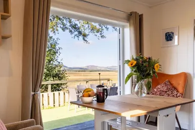 a table with a vase of flowers and a window at East Kip - Dog Friendly in Penicuik