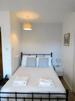 a bedroom with a bed with two towels on it at Modern bright studio apartment in south Glasgow in Glasgow