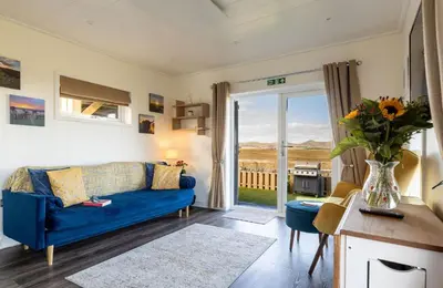 a living room with a blue couch and a vase of flowers at South Black Hill in Penicuik