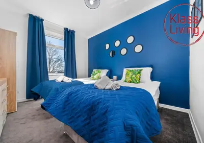 a blue bedroom with two beds and a blue wall at Coats Street Apartment by Klass Living Coatbridge in Coatbridge