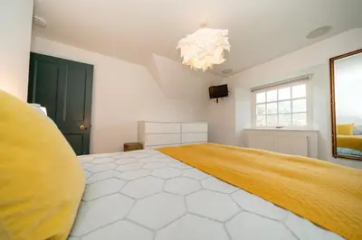a large bedroom with a large bed with a yellow blanket at Sleeps 10. The Old pink library by loch and river in Lochearnhead