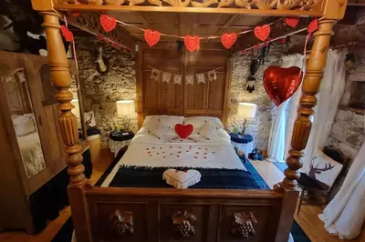 a bedroom with a wooden bed with a heart on it at Baidland Escapes 2 bedroom cottage With hot tub in Dalry