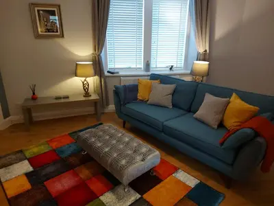 a living room with a blue couch and a colorful rug at Black Cat Cottage in Moffat