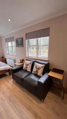 a black leather couch in a living room with two windows at Wrens nest in Newton Stewart