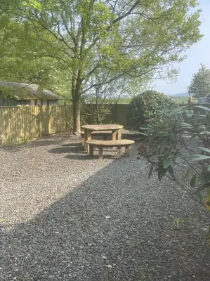 a wooden picnic table in a backyard with a tree at Wrens nest in Newton Stewart