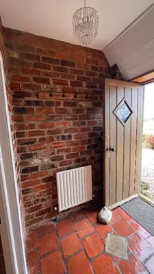a brick wall with a radiator next to a door at Popsal in Kirkcowan