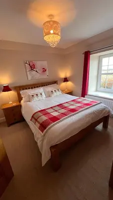 a bedroom with a large bed and a chandelier at Popsal in Kirkcowan