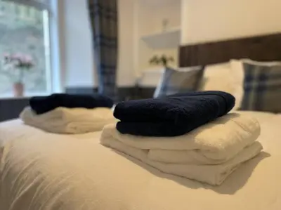 a pile of towels sitting on top of a bed at Strathisla Garden Apartment, Oban in Oban