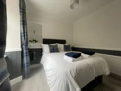 a bedroom with a bed with white sheets and blue pillows at Strathisla Garden Apartment, Oban in Oban
