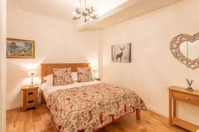 a bedroom with a bed and a mirror on the wall at The Mews - a cottage with a spectacular lake view in Port of Menteith