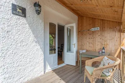 a porch of a house with a table and a door at The Stable - cottage with a spectacular lake view in Port of Menteith