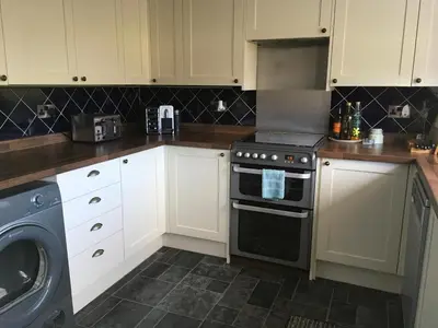 a kitchen with a stove and a washing machine at Minton cottage in Leadhills