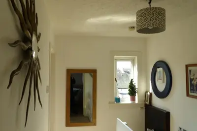 a living room with a mirror and a window at Aigas Cottage in Glasgow