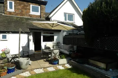 a patio with an umbrella and chairs at Aigas Cottage in Glasgow