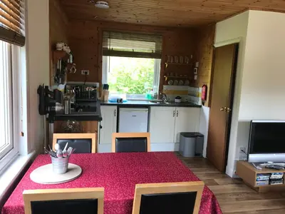 a kitchen with a table with a red table cloth at Glengarry Lodge in Tyndrum