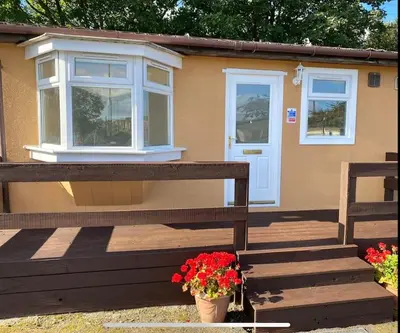 a house with a bench and flowers in front of it at Semi-detached chalet at Maryville Caravan Site - Uddingston, Glasgow in Uddingston
