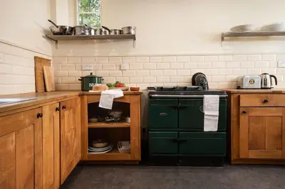 a kitchen with a green stove and wooden cabinets at Mossfennan House in Drummelzier