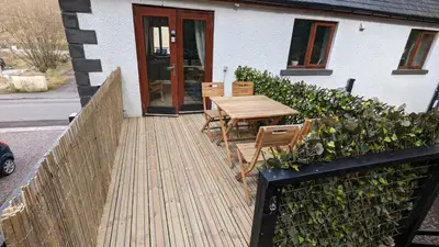 a wooden deck with a table and chairs in front of a house at Eakie House Apartments - Kinlochleven in Kinlochleven