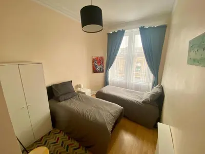 a small bedroom with two beds and a window at Paisley Pad Glasgow Gateway second floor flat in Paisley