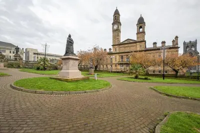 a statue in front of a building with a clock tower at Paisley Pad Glasgow Gateway second floor flat in Paisley
