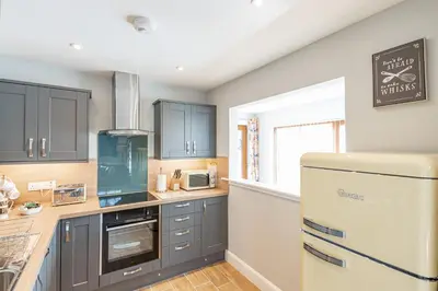a kitchen with blue cabinets and a white refrigerator at Kestrel Lodge 2 with Hot Tub in Newton Stewart