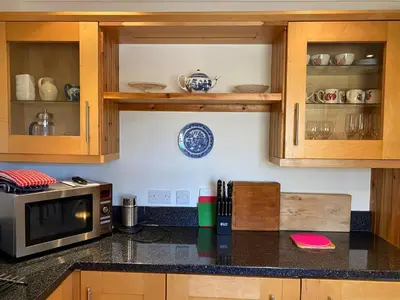 a kitchen with wooden cabinets and a microwave oven at Private detached cottage sleeps 4 in Crieff