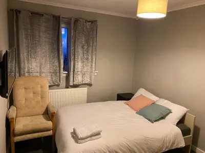 a bedroom with a bed and a chair and a window at Culbin Lodge in Glasgow