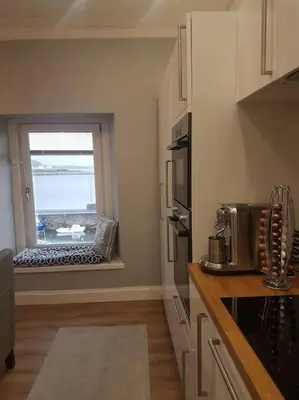 a kitchen with a window with a view of the ocean at Wee Harbour View in Millport