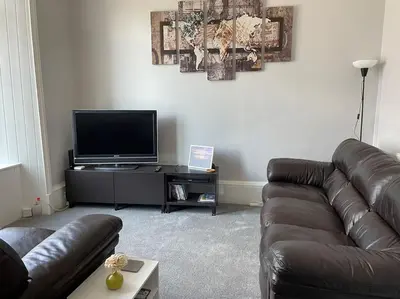 a living room with a leather couch and a flat screen tv at 5 minutes from Loch Lomond - Newly Renovated Ground Floor 1-Bed Flat in Bonhill