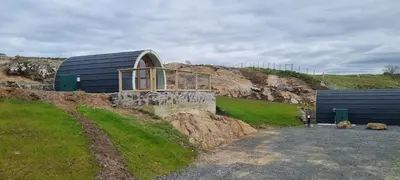 a building on top of a hill with a house at Fairhead Glamping Pods in Ballycastle