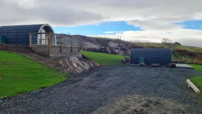 a gravel road next to a building on a hill at Fairhead Glamping Pods in Ballycastle