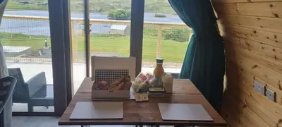a table with a box of food and a bottle of beer at Fairhead Glamping Pods in Ballycastle