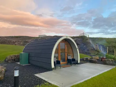 a black and white dome shaped building with a patio at Fairhead Glamping Pods in Ballycastle