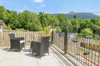a patio with chairs and a table and a fence at Ben View in Arrochar