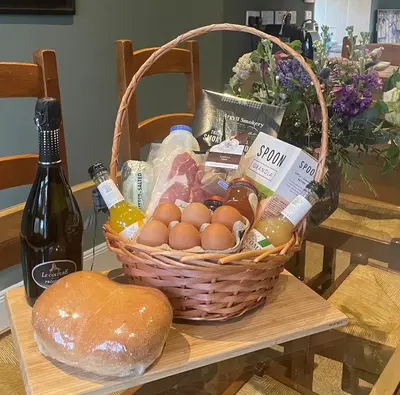 a basket of eggs and a bottle of wine on a table at Luxury Garden Cottage in Dalry