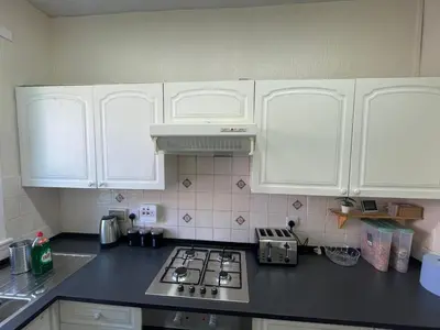 a kitchen with white cabinets and a stove top oven at Earls Lodge in Whiteinch