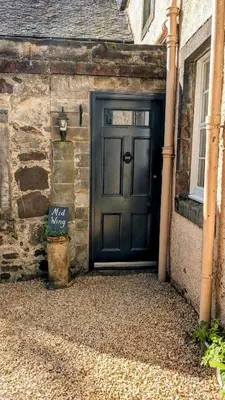 a black door on the side of a stone building at Mid Cottage at Powis House Estate in Stirling